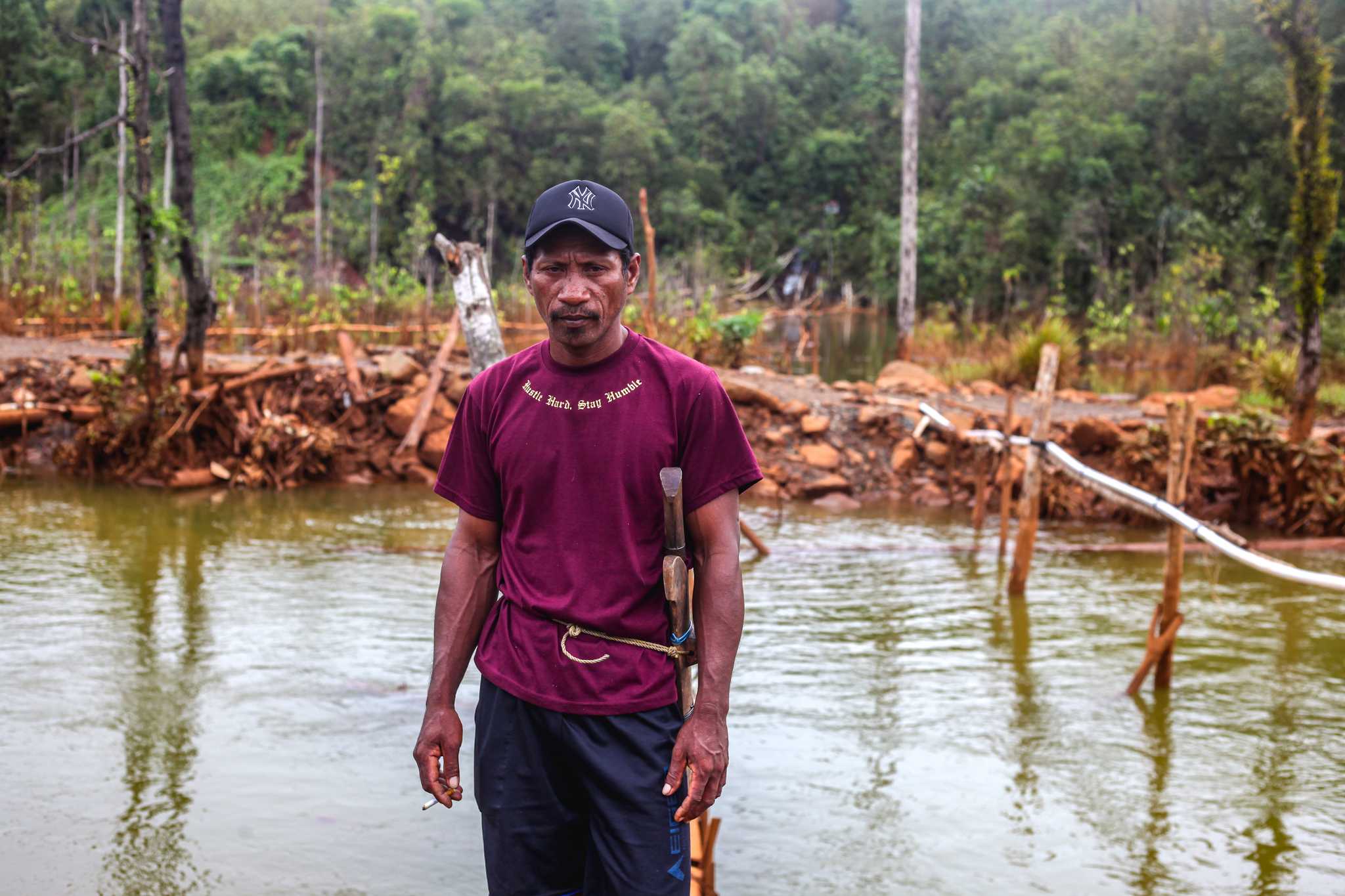 Photo of Mann Noho standing by pipes carrying water from Kawasi spring into local homes.