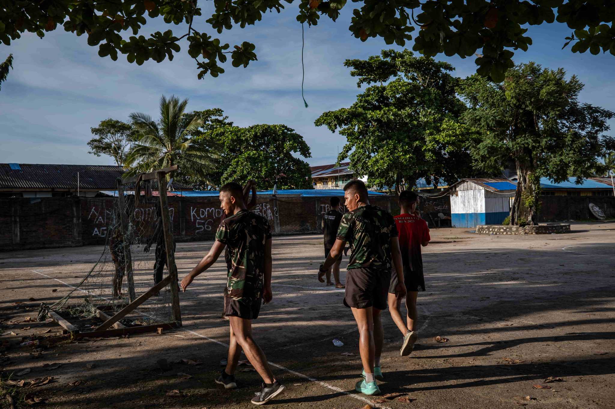Soldiers in athletic clothing walk across a concrete football field